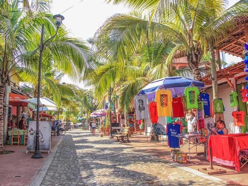Cobbled street in Sayulita lined with palms and stalls selling clothes and crafts