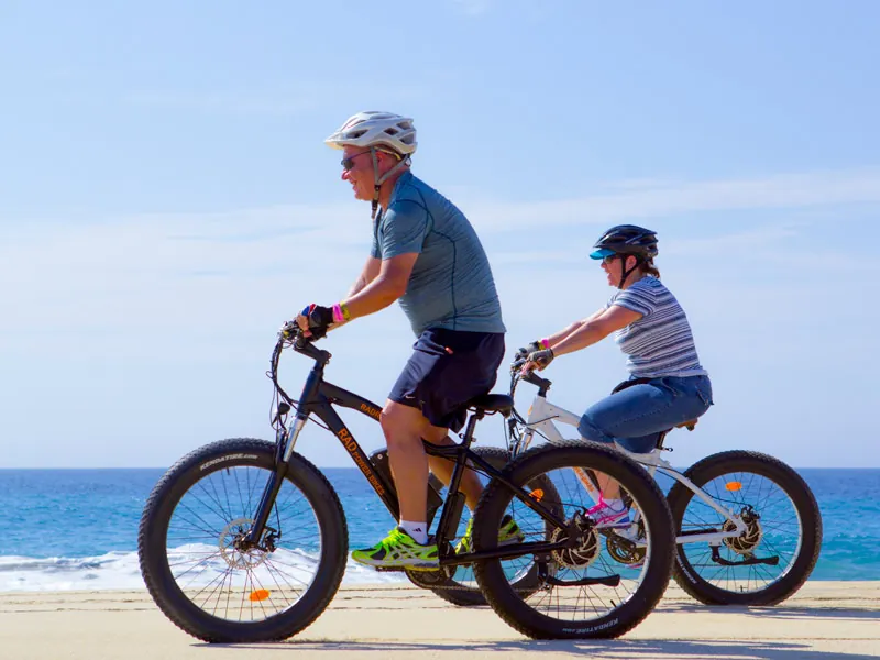 Couple riding electric fat bikes along the shoreline