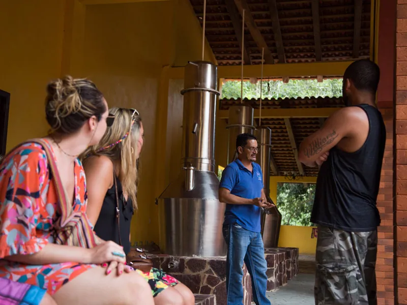 Guide explaining the stainless-steel stills to guests at a tequila distillery