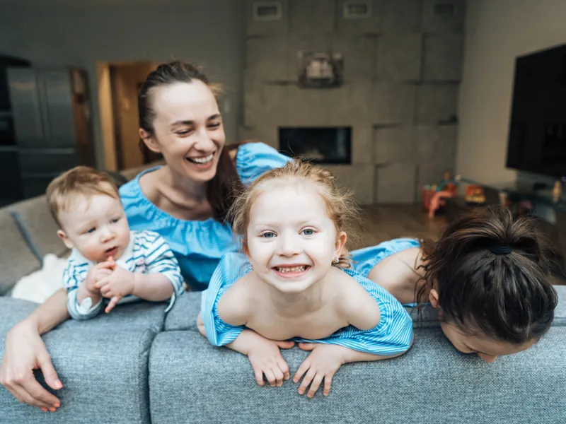 Babysitter playing with three children on a sofa