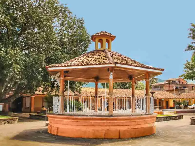 Terracotta-roofed bandstand in a small town square with tile-roofed houses behind