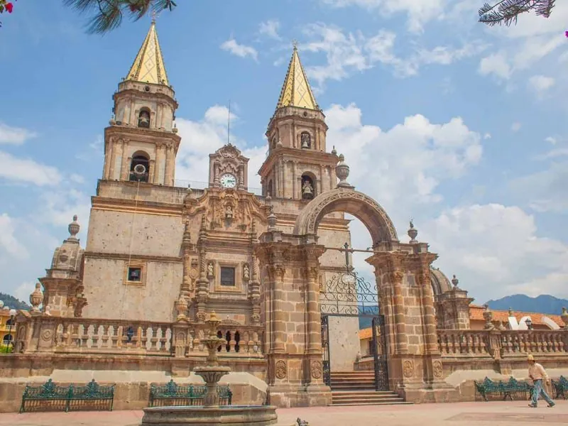 Stone basilica of Talpa with two pointed spires and an arched gateway under a blue sky