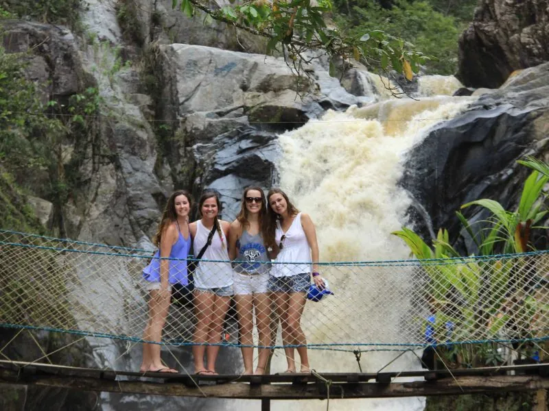 Friends on a rope suspension bridge above a rushing waterfall in the Sierra Madre