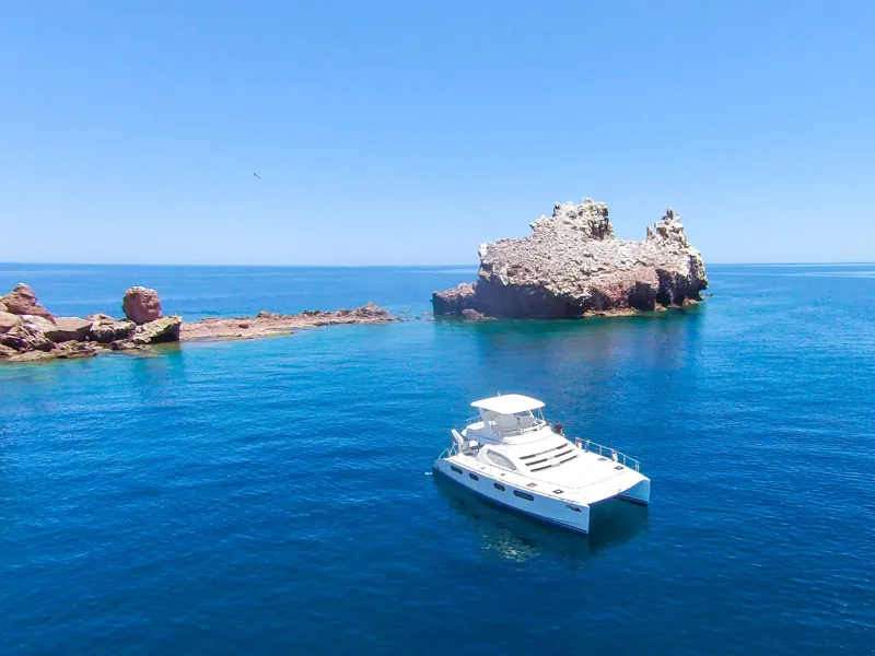 Catamaran anchored in deep blue water beside rocky islets