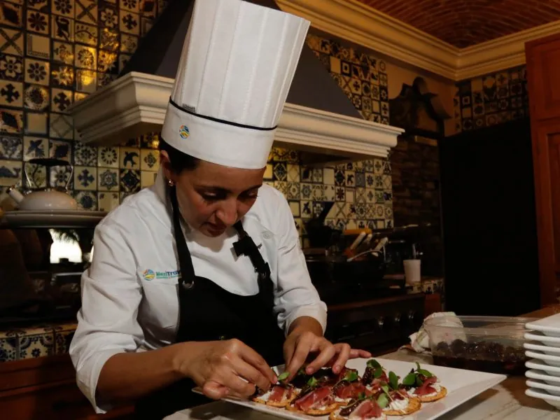 Chef preparing a dish in a tiled Mexican kitchen