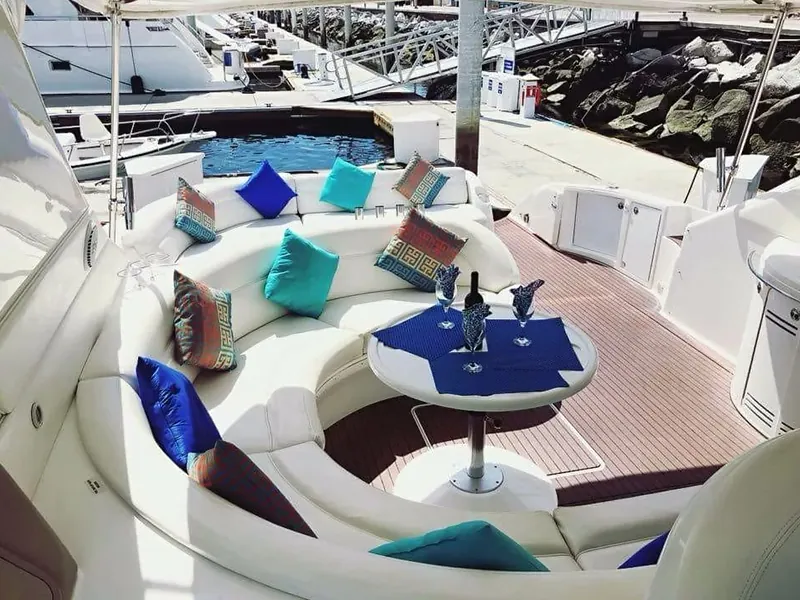 Cockpit lounge with white seating, colored cushions and a set table, moored in the marina