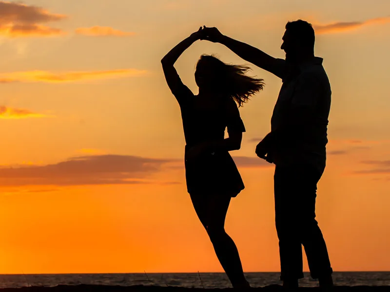 Couple dancing in silhouette against an orange sky