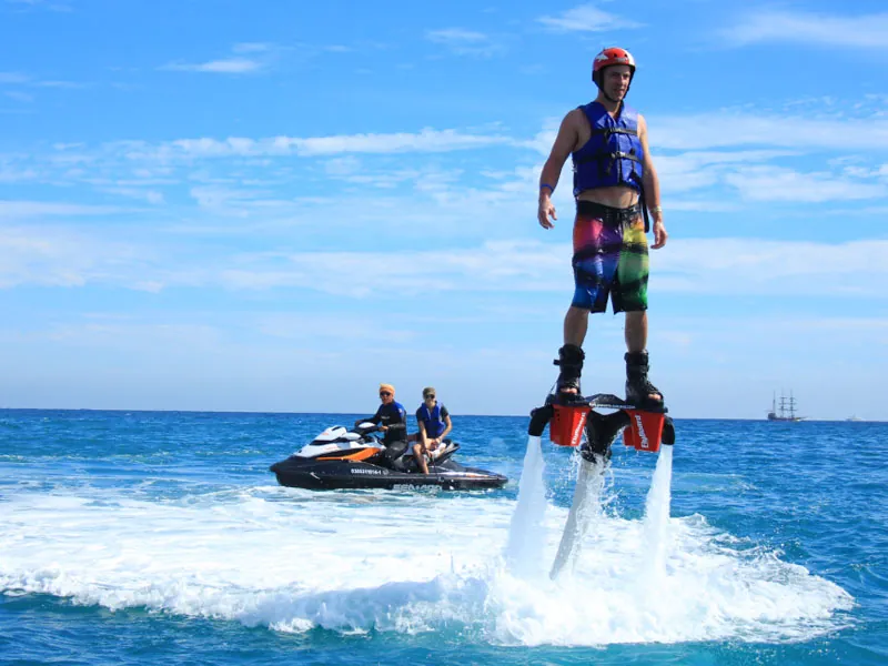Flyboarder standing above the sea on twin water jets, a jet ski behind