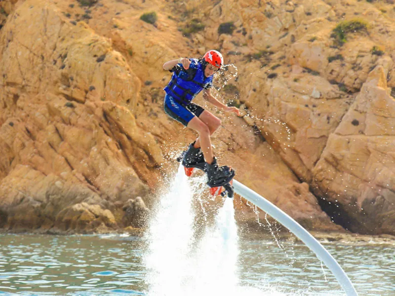 Flyboarder hovering in front of golden granite rocks
