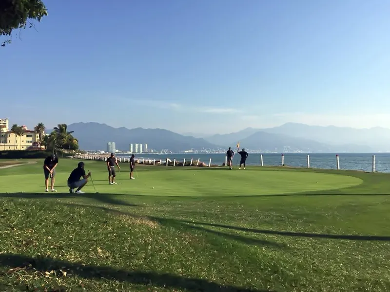 Golfers on a green overlooking Banderas Bay and the mountains