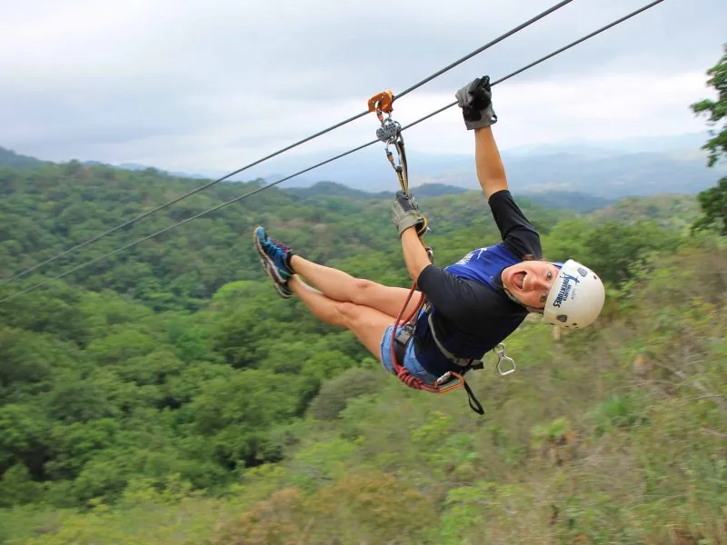 Guest flying down a zip-line above the jungle-covered hills