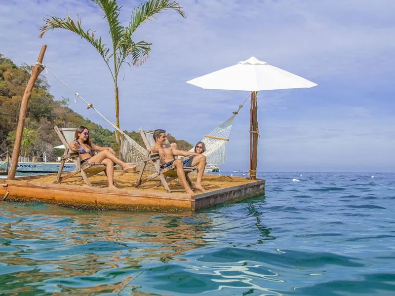 Guests lounging on a floating deck with an umbrella