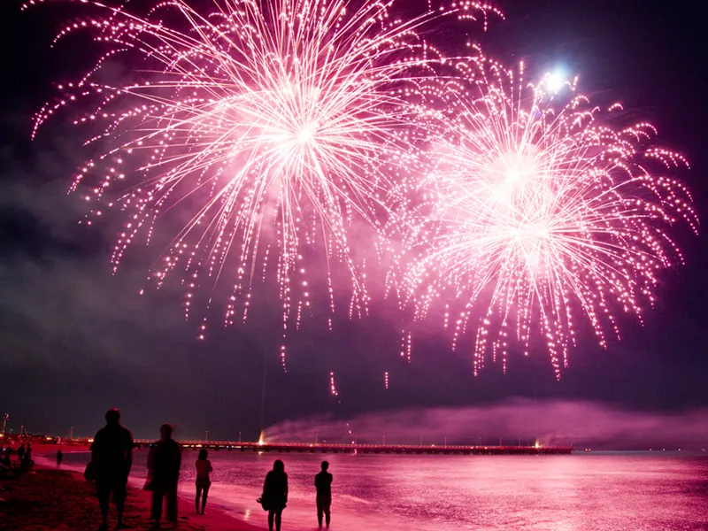Guests on the beach watching pink fireworks