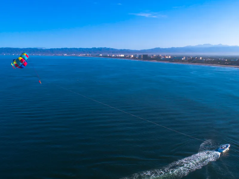 Parasailer high above Banderas Bay with the coastline of Puerto Vallarta in the distance