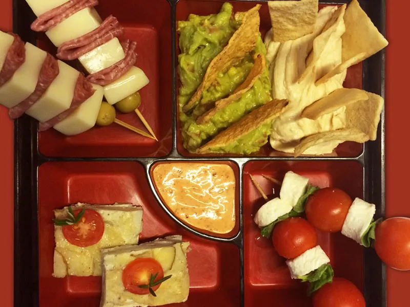 Tray of hors d’oeuvres with guacamole tostadas, salami skewers and tomato-mozzarella bites