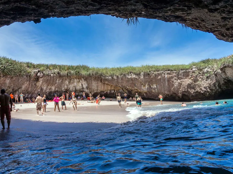 The hidden beach at the Marietas Islands seen from inside its rock arch, visitors on the sand
