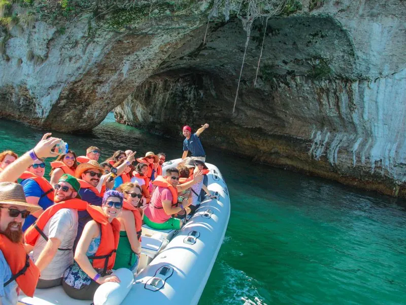 Passengers in red life vests on an inflatable boat inside a sea cave