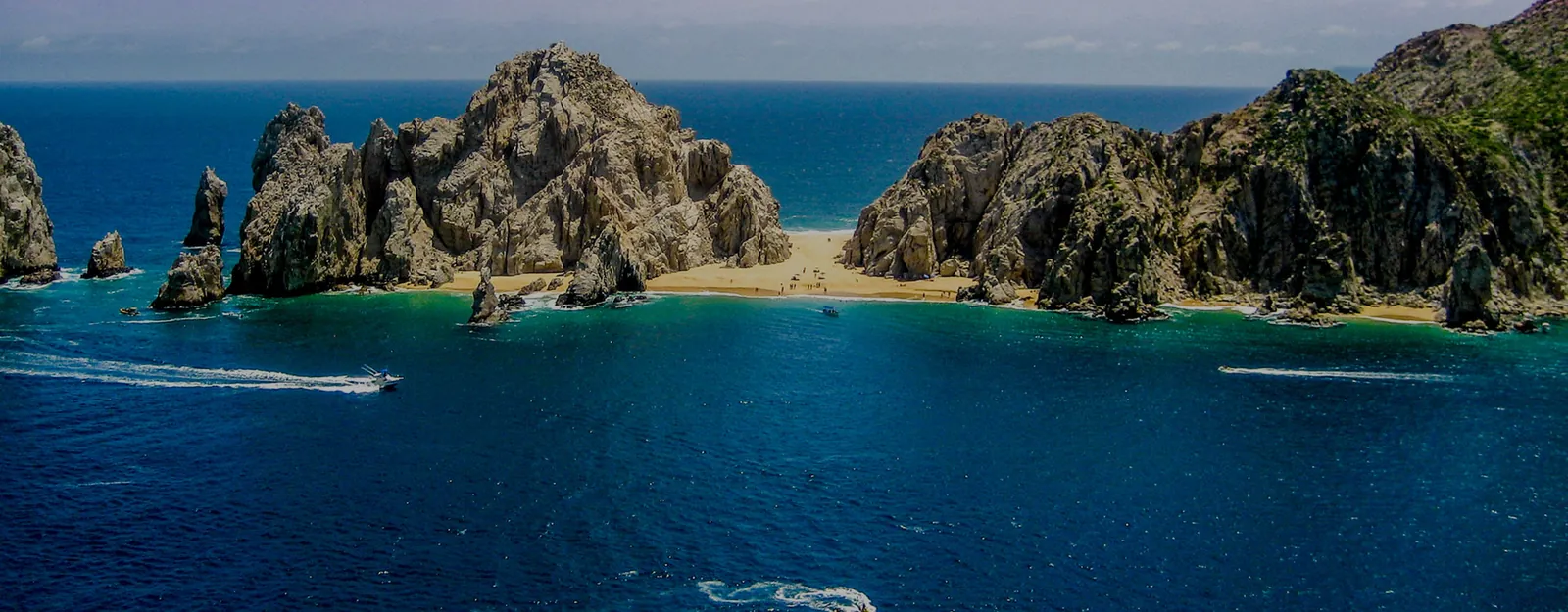 Aerial view of Land’s End and Lover’s Beach in Cabo San Lucas with boats on blue water