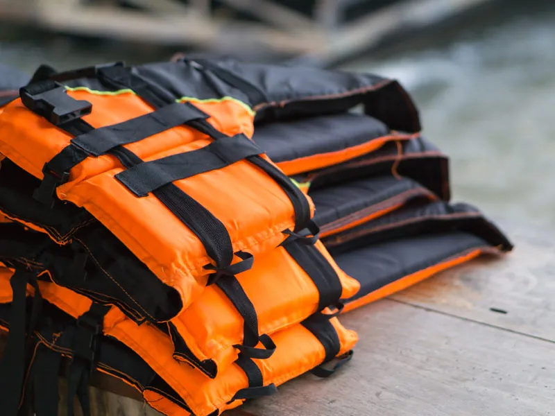 Stack of orange and black life jackets on a boat deck