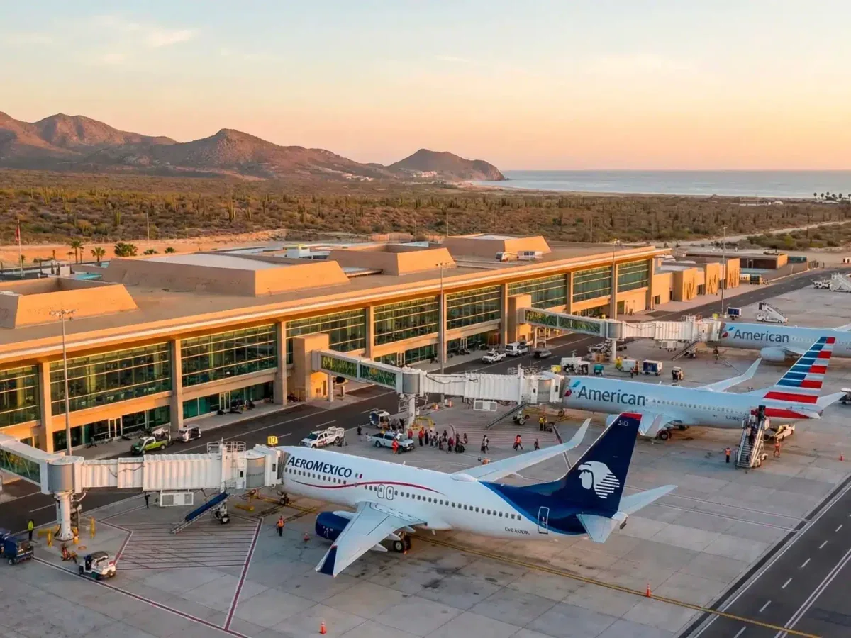 Aerial view of Los Cabos International Airport terminal with aircraft at the gates, desert hills and the sea beyond