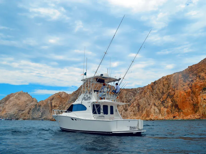 Luhrs 35 sportfisher with outriggers below the red cliffs of Cabo San Lucas
