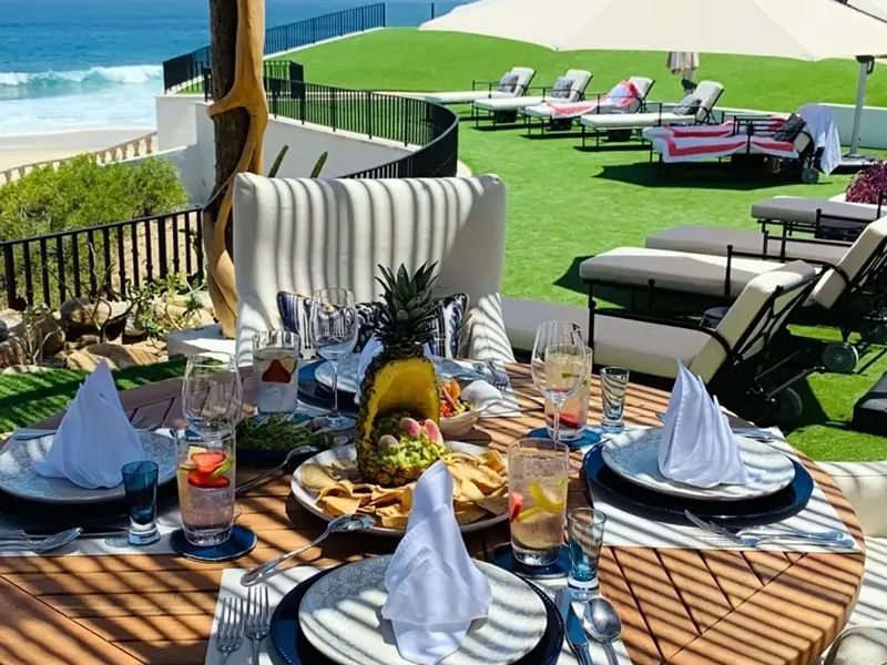 Table set for lunch on a villa terrace above a lawn and the ocean