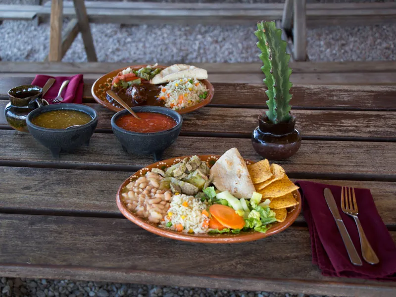 Mexican lunch plates with rice, beans and salsas on a wooden table