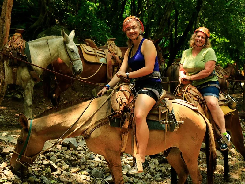 Two guests in helmets riding mules on a rocky trail at the end of the ATV and canopy combo