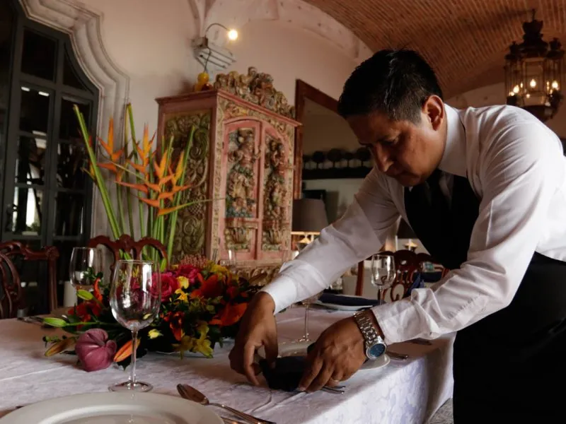Waiter folding napkins beside wine glasses on a formal dining table
