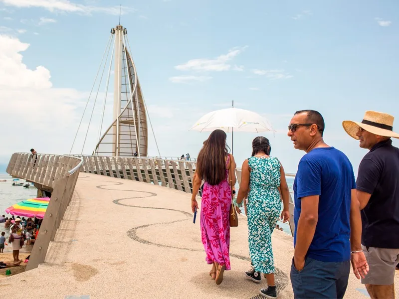Guests walking onto the sail-shaped Los Muertos pier on a sunny day in Puerto Vallarta