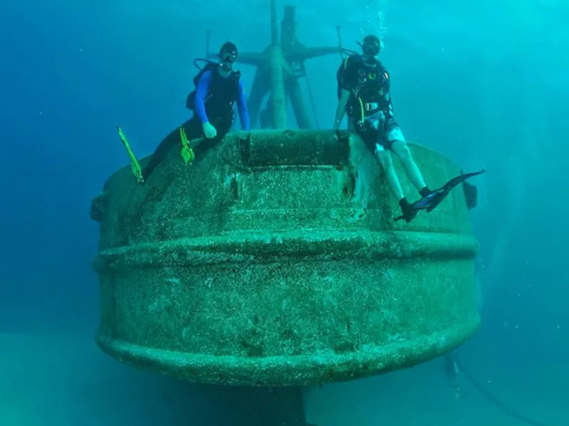 Two divers sitting on the encrusted hull of the Princesa shipwreck off Mismaloya
