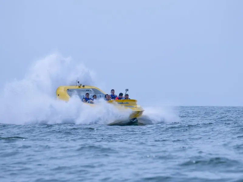 Jet boat throwing a wide wake of spray on open blue water