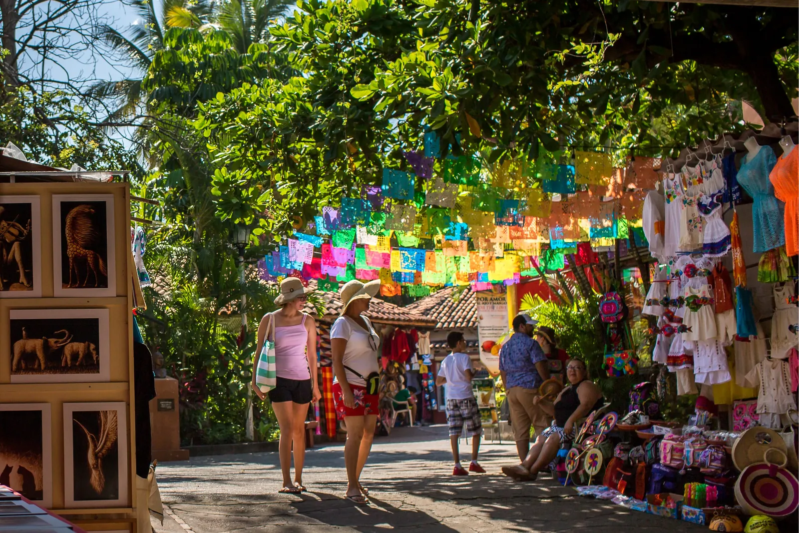 Colorful papel picado strung over a shaded market lane on Isla Río Cuale