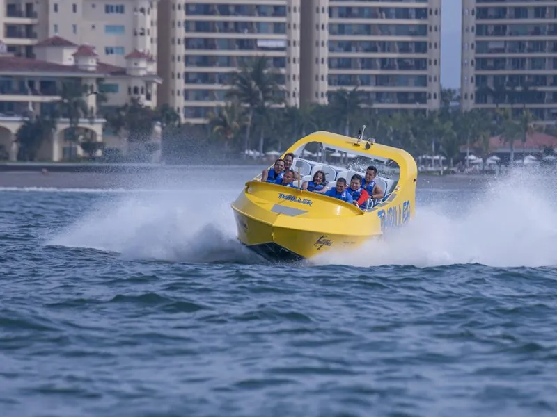 Yellow jet boat speeding past the towers of Marina Vallarta