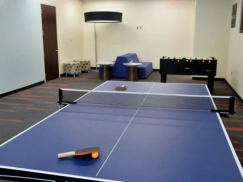 Blue ping-pong table with paddle and ball in a games room