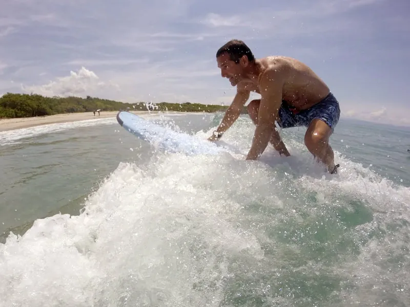 Surfer in dark shorts pushing up on a white foam board in the whitewater near Punta Mita