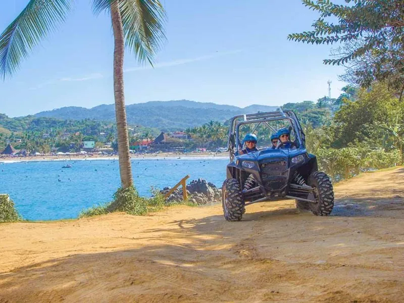 Guests in a Polaris RZR buggy on a bluff above the bay and beach of Sayulita