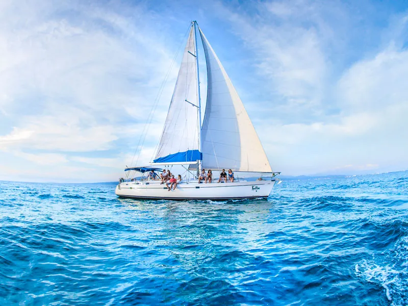 Sailing yacht heeling across deep blue water beneath streaks of cloud