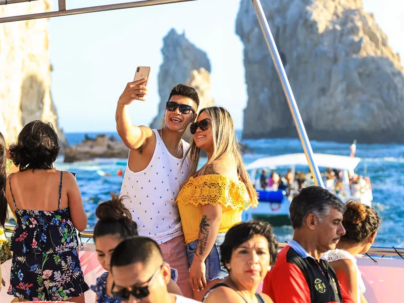 Couple taking a selfie aboard the catamaran with the Land’s End rocks behind