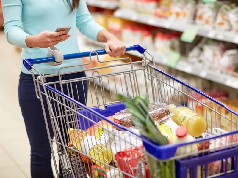 Shopping cart full of groceries in a supermarket aisle