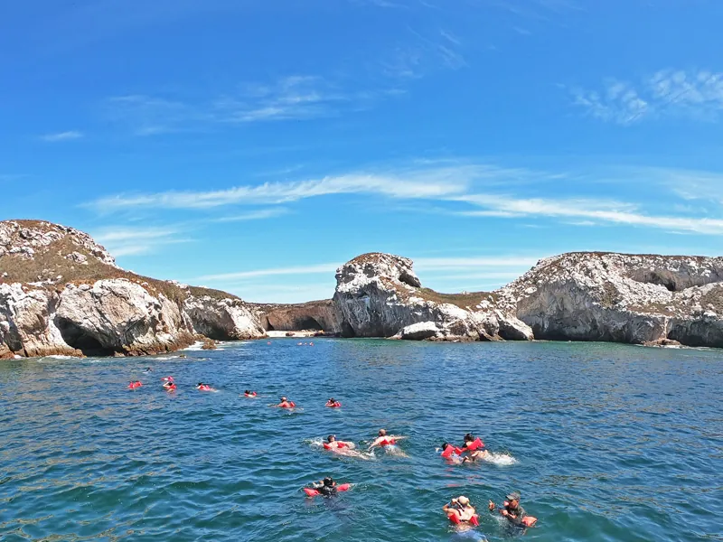 Group of snorkelers in red life vests swimming between the rocky Marietas Islands