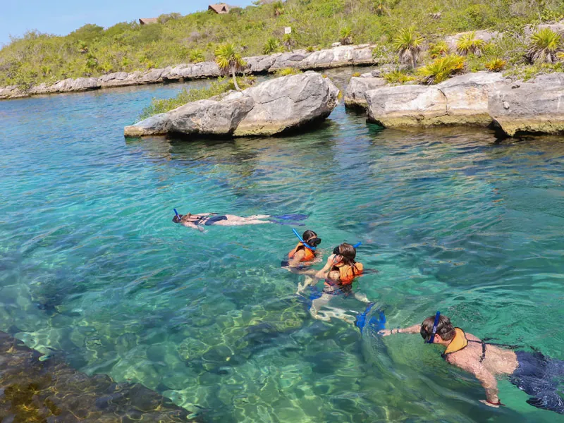 Snorkelers in life jackets floating over clear water between limestone rocks at Yalku lagoon