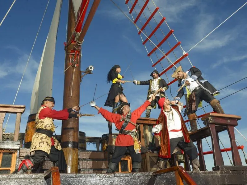 Costumed pirates crossing swords on the deck of the ship beneath the rigging