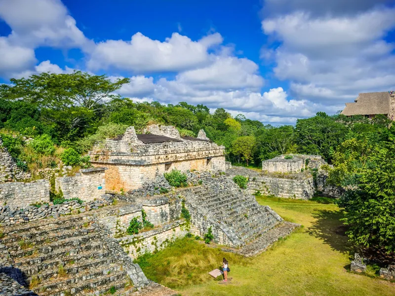 Terraced stone ruins and grassy plazas at Ek Balam surrounded by trees