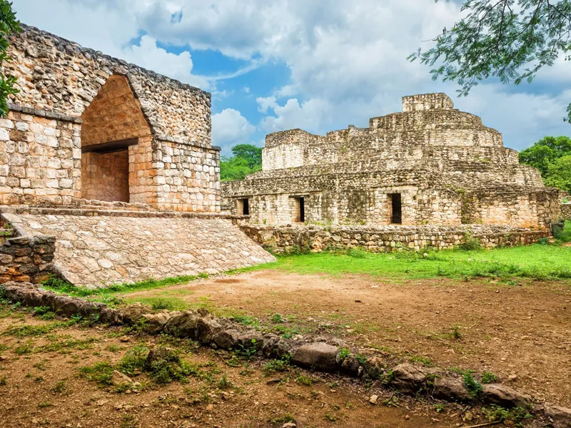A corbelled stone arch and the oval palace at Ek Balam on a sunny day