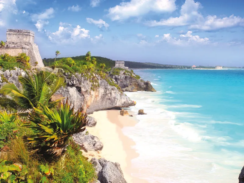 A sandy cove below the cliffs and ruins of Tulum, with turquoise sea stretching north