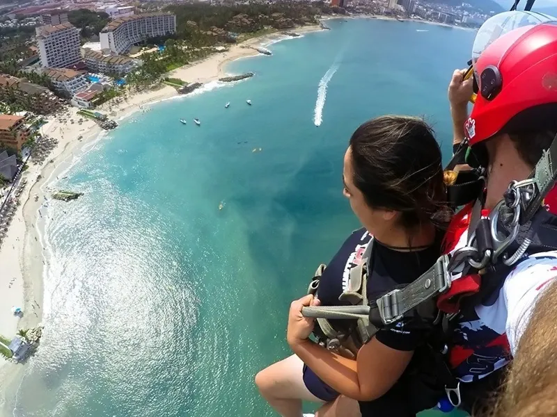 Tandem skydivers looking down on a beach, hotels and boats on Banderas Bay