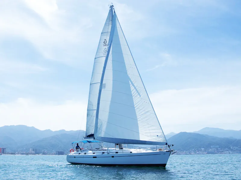 Sailboat under full sail on Banderas Bay with the Sierra Madre and Puerto Vallarta behind