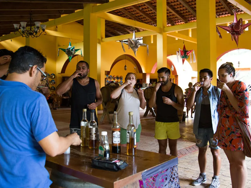 Guests sipping tequila at a tasting bar in a yellow hall hung with piñata stars