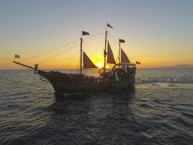 Silhouette of the pirate ship on the bay as the sun sets behind its masts